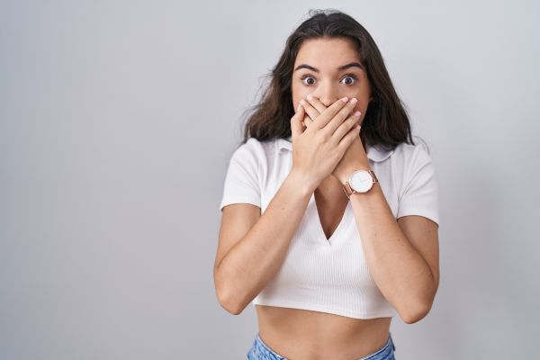 Mujer joven cubriendose la boca como una señal de qué está teniendo episodios de hipo y no los puede parar