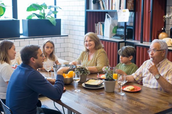 Familia platicando en una mesa mostrando la importancia de tener una red de apoyo con los hijos.