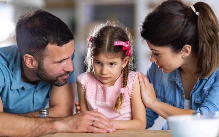 Papá y mamá platican con su niña compartiendo valores y aprendizajes en familia