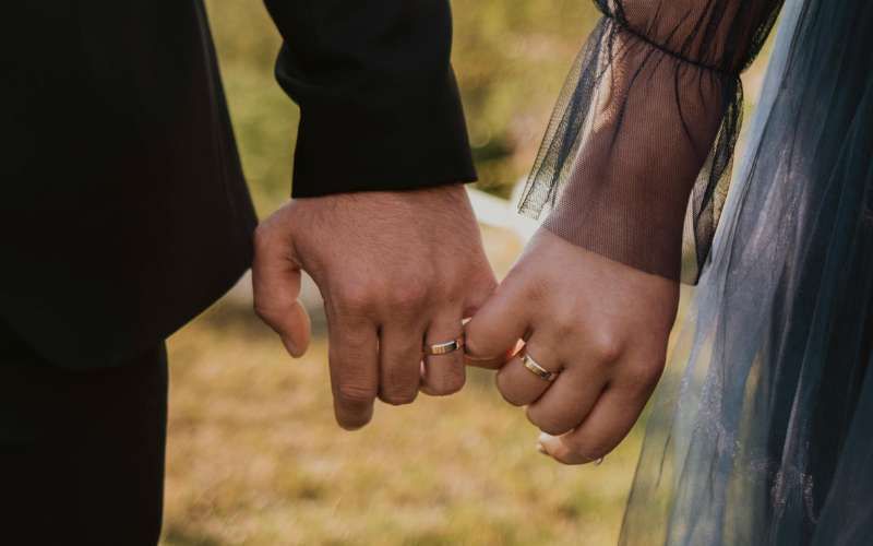 Pareja tomada de la mano mostrando sus argollas de matrimonio