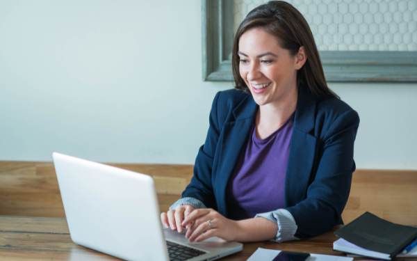 Reclutadora revisando en su laptop un CV bien hecho para trabajo remoto y mostrando satisfacción con la candidata"
