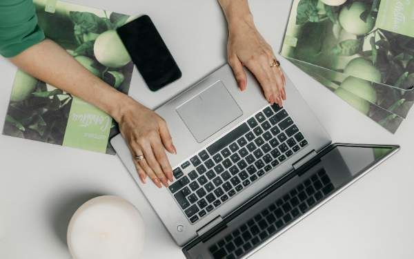 Manos de una mujer trabajando en su laptop mientras actualiza su CV para aplicar a un trabajo remoto"