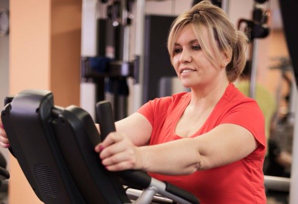 Mujer madura disfrutando su rutina de ejercicio cardiovascular en el gimnasio con actitud positiva.