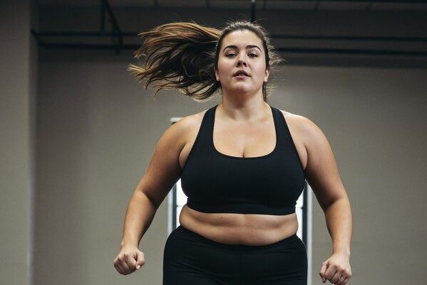 Mujer con cuerpo real haciendo ejercicio en el gimnasio con actitud positiva y confianza.