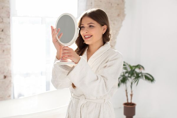 Mamá frente al espejo sonriendo, practicando una forma más amable y respetuosa de hablarse a sí misma