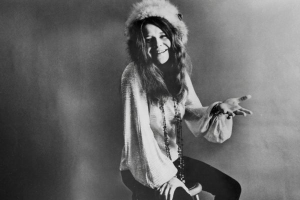 Retrato de Janis Joplin sonriendo con sombrero de piel, capturando su esencia rebelde y honesta en el rock.