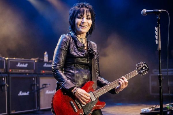 Una foto de Joan Jett, la chica del rock, tocando su guitarra con orgullo y determinación.