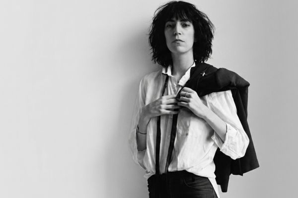 Retrato en blanco y negro de Patti Smith con su mítica imagen punk y literaria, posando con chaqueta al hombro.