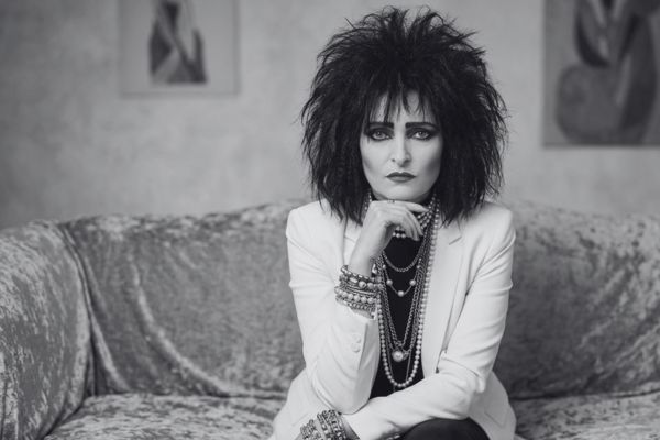 Retrato de Siouxsie Sioux con su mítica estética gótica, posando con su maquillaje negro y vestuario dramático.