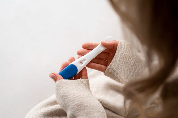 Primer plano de manos sosteniendo un test de embarazo positivo, representando las dudas y el inicio de la gestación.
