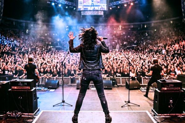 Vista de espaldas de una rockera frente a una multitud en un concierto, representando a las mujeres más influyentes del rock y el indie