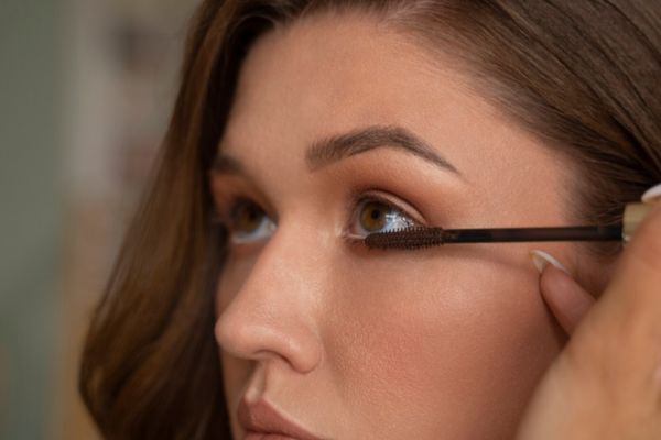 Mujer usando un rímel de calidad para cuidar sus pestañas y sus ojos.