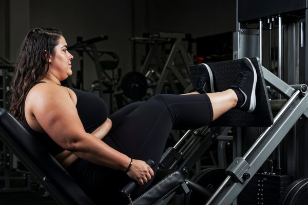 Mujer curvy haciendo ejercicios de fuerza en un gimnasio.