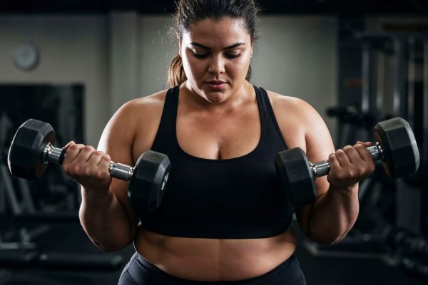 pesas volumen mujer Mujer haciendo ejercicios de fuerza con pesas con un entrenamiento adecuado.