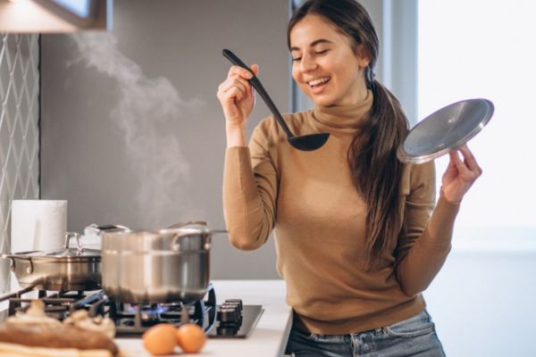 Mujer joven cocinando en una estufa a gas en su casa