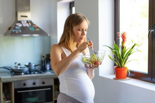 manejar antojos en el embarazo sin descuidar alimentacion Mujer comiendo de manera saludable como una estrategia de controlar los antojos.